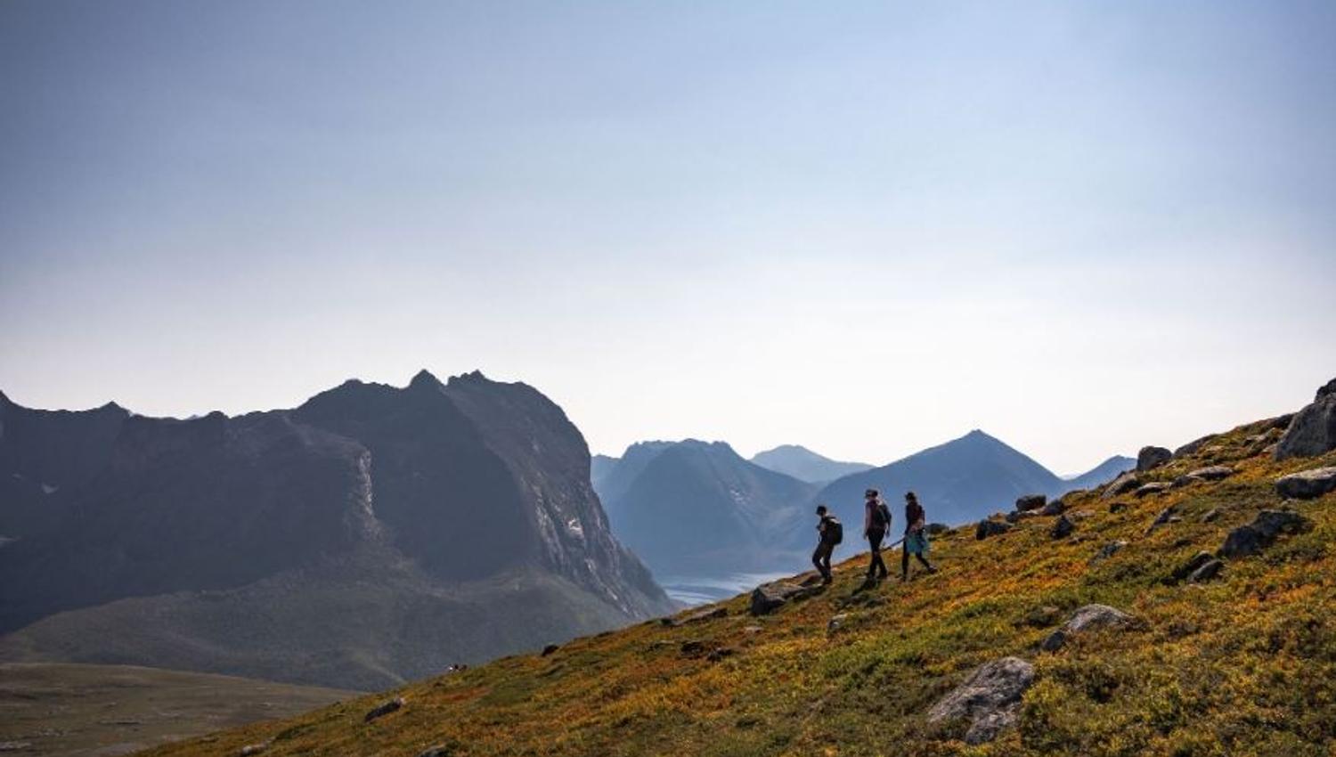 Three guests hiking with mountains in the background