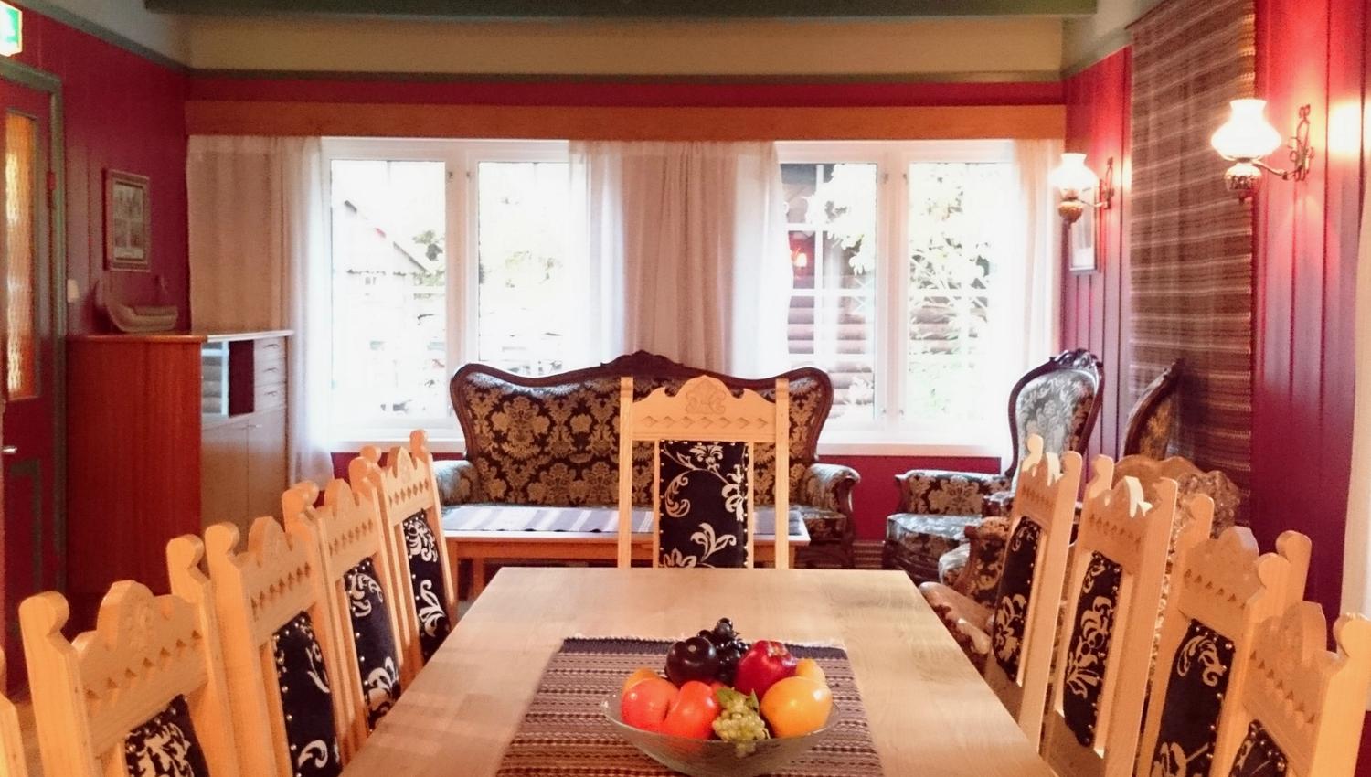 Bright and cozy lounge at Ullensvang Gjesteheim featuring traditional furniture, embroidered details and views toward the garden.