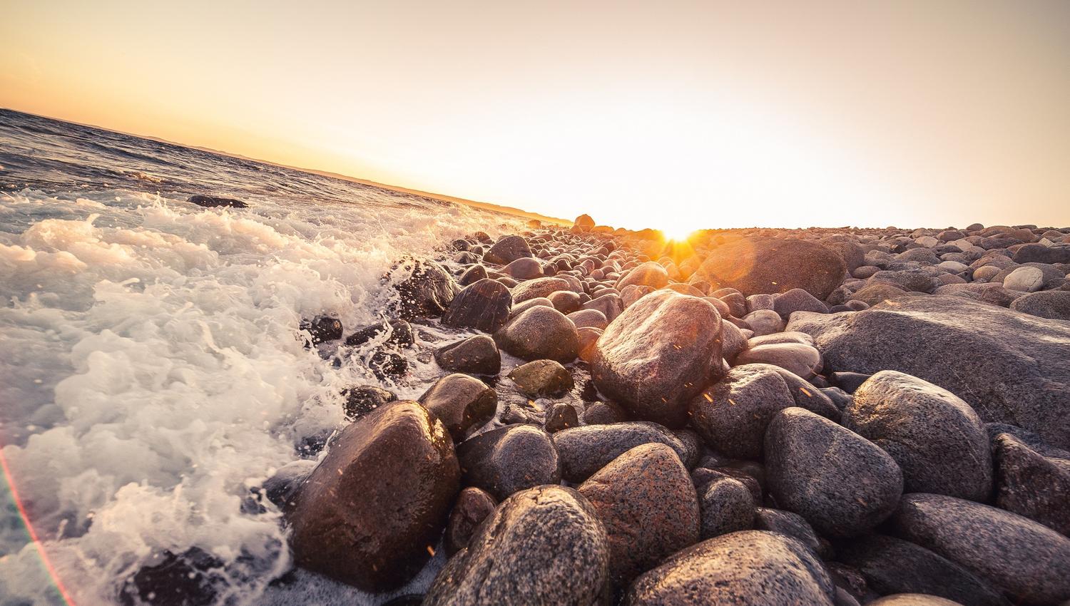 Rolling stones on Mølen in the water with sunset
