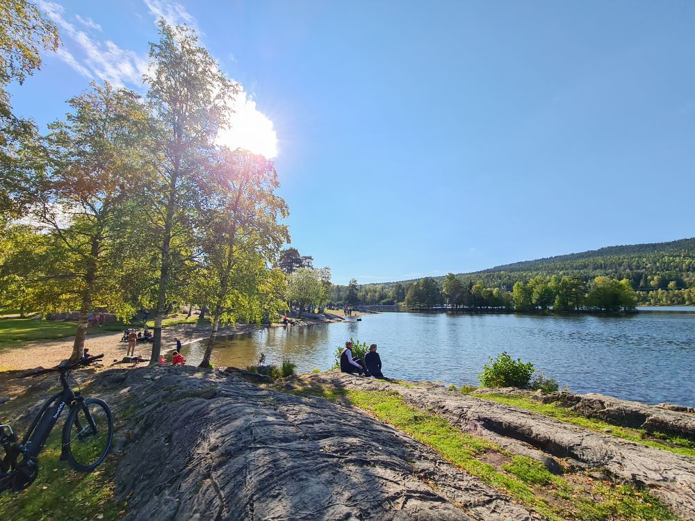 The beach at Sognsvann with people sitting by the water
