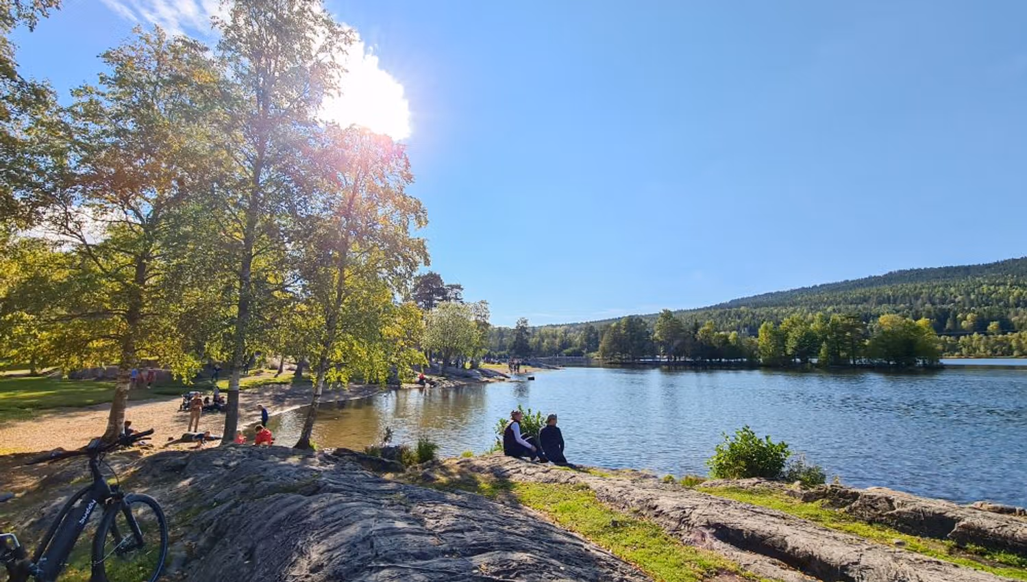 The beach at Sognsvann with people sitting by the water