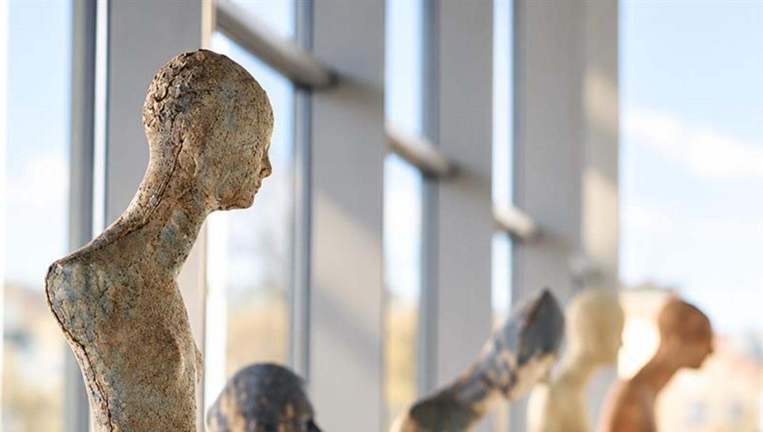 Several figurative sculptures displayed on white pedestals in a bright exhibition space at Larvik Kunstforening's Galleri Bølgen.