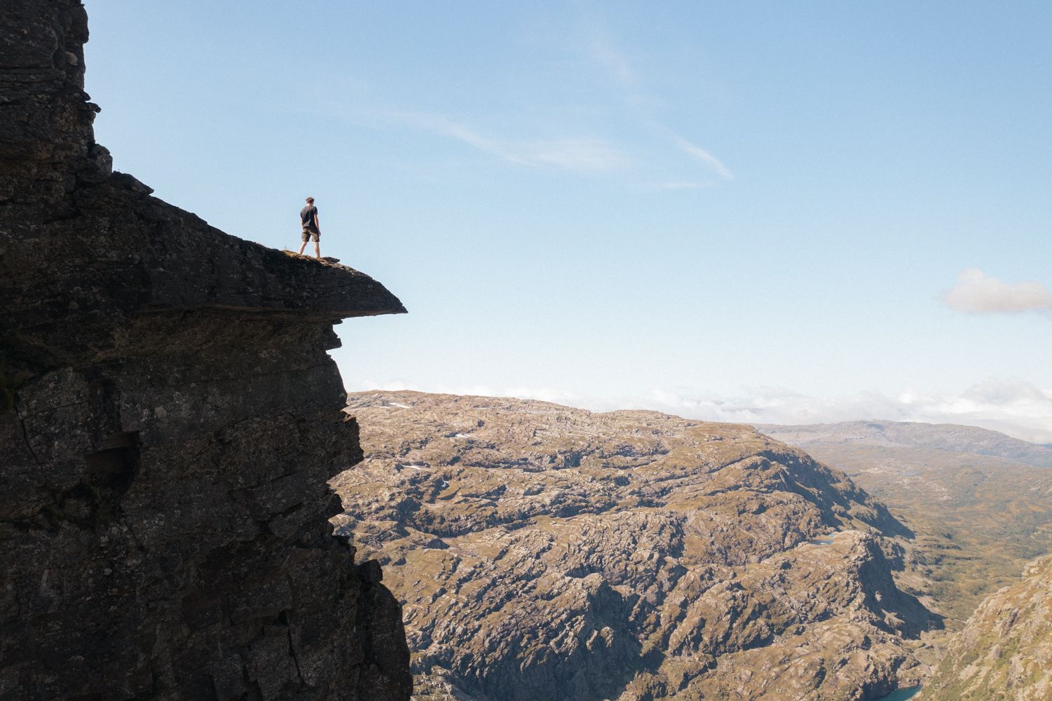 Person står på en massiv fjelltopp og ser utover fjellandskapet.