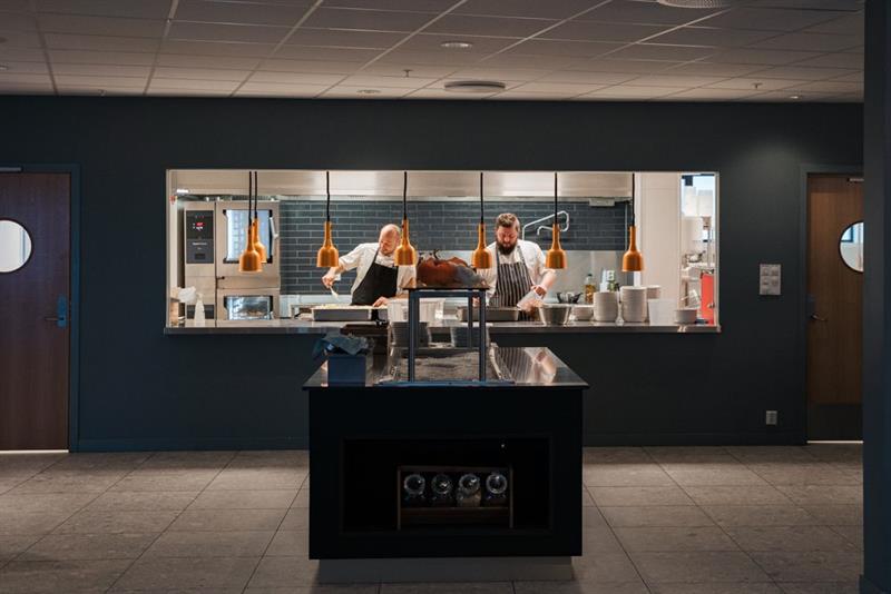 Two chefs are preparing food in the kitchen of an restaurant