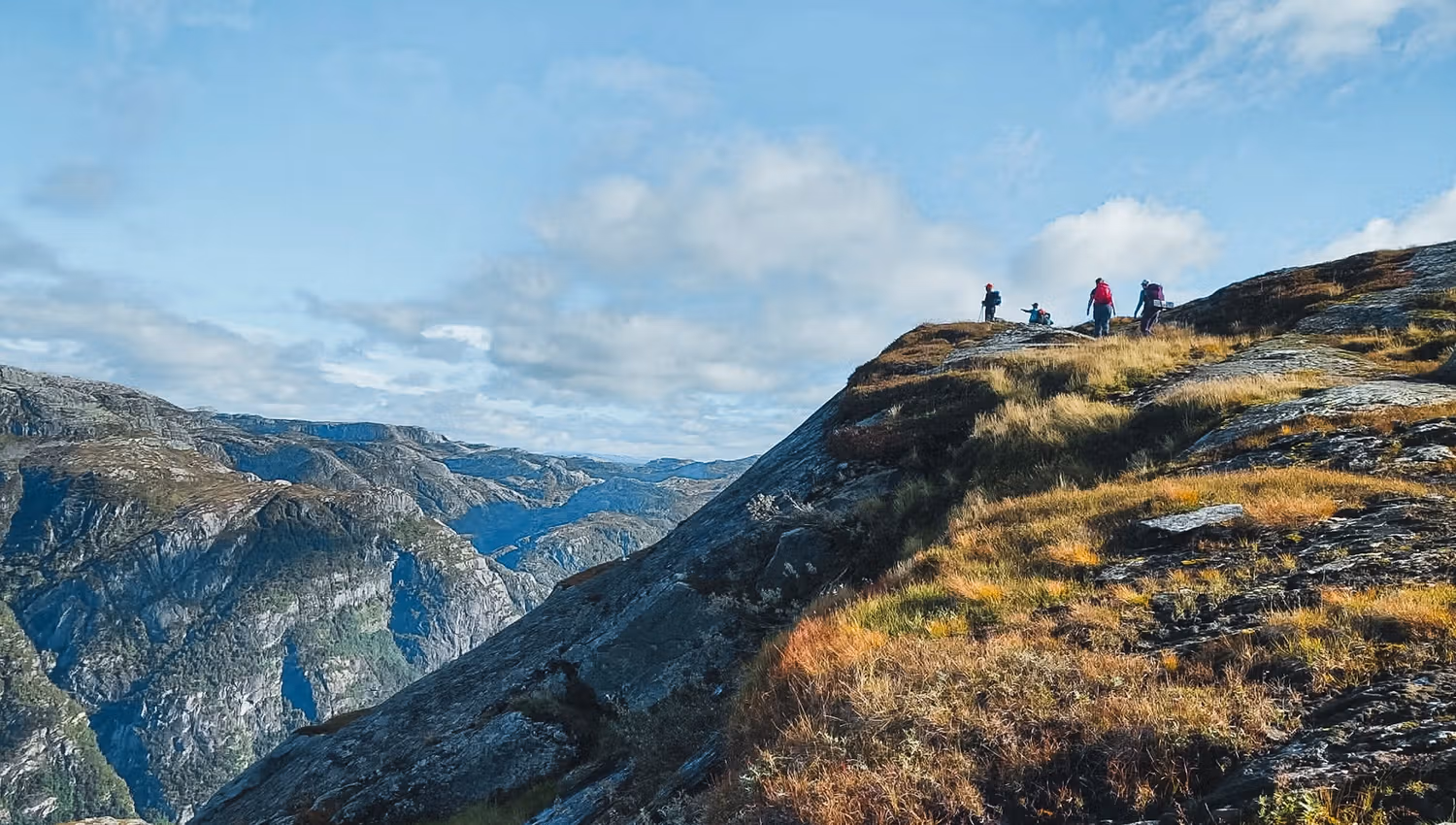Hikers on a mountain ridge overlooking dramatic landscapes in Hardanger, Norway, ideal for hiking and outdoor adventures