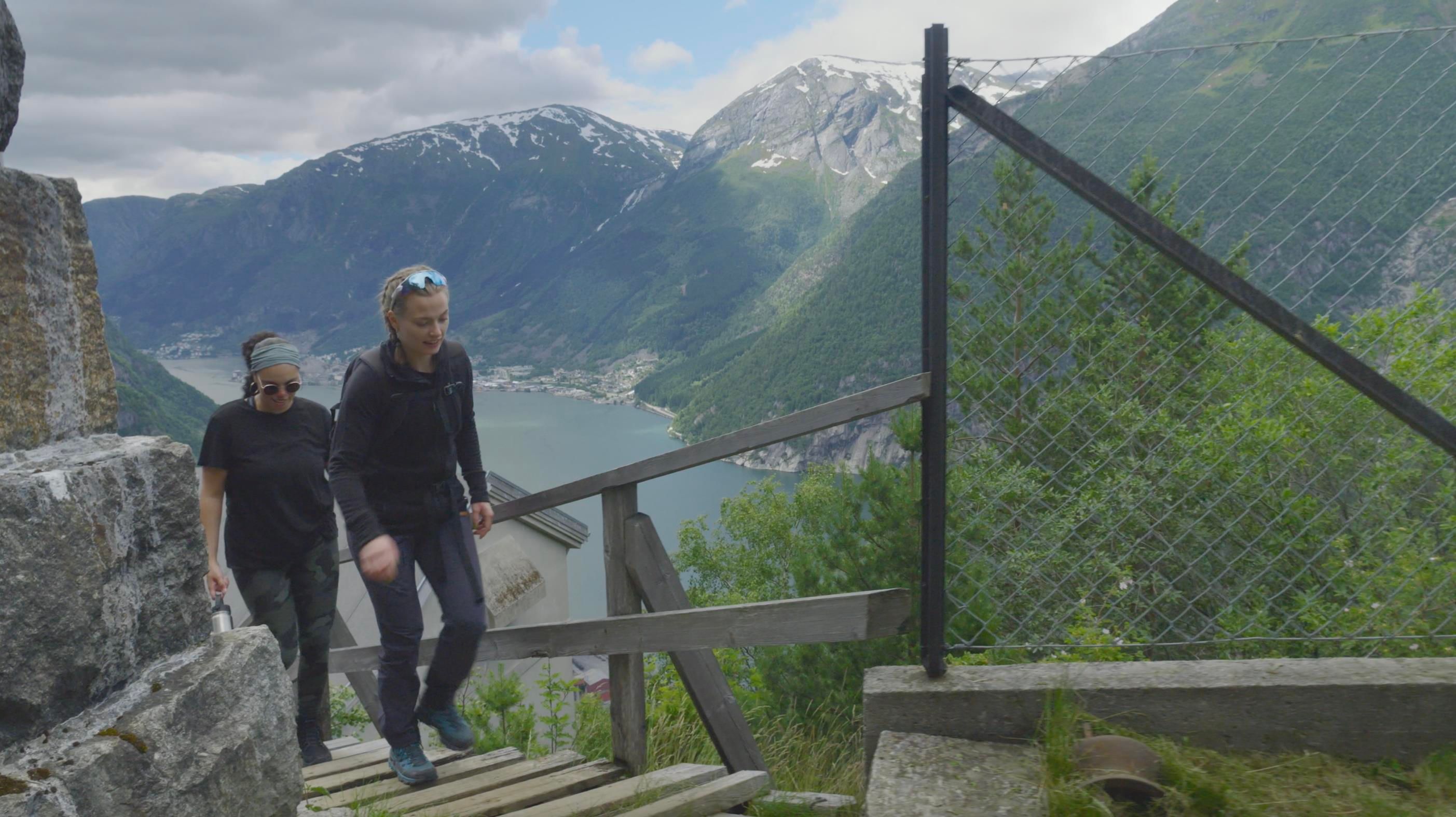 Two hikers making their way up to Lilletopp, enjoying spectacular views of the fjord and mountains.