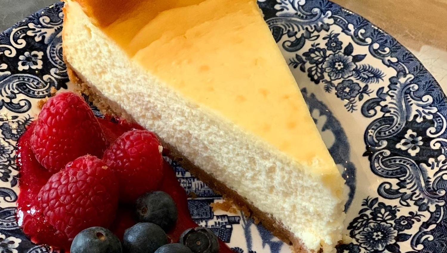 Ostekake med bær og saus på blåhvitt fat