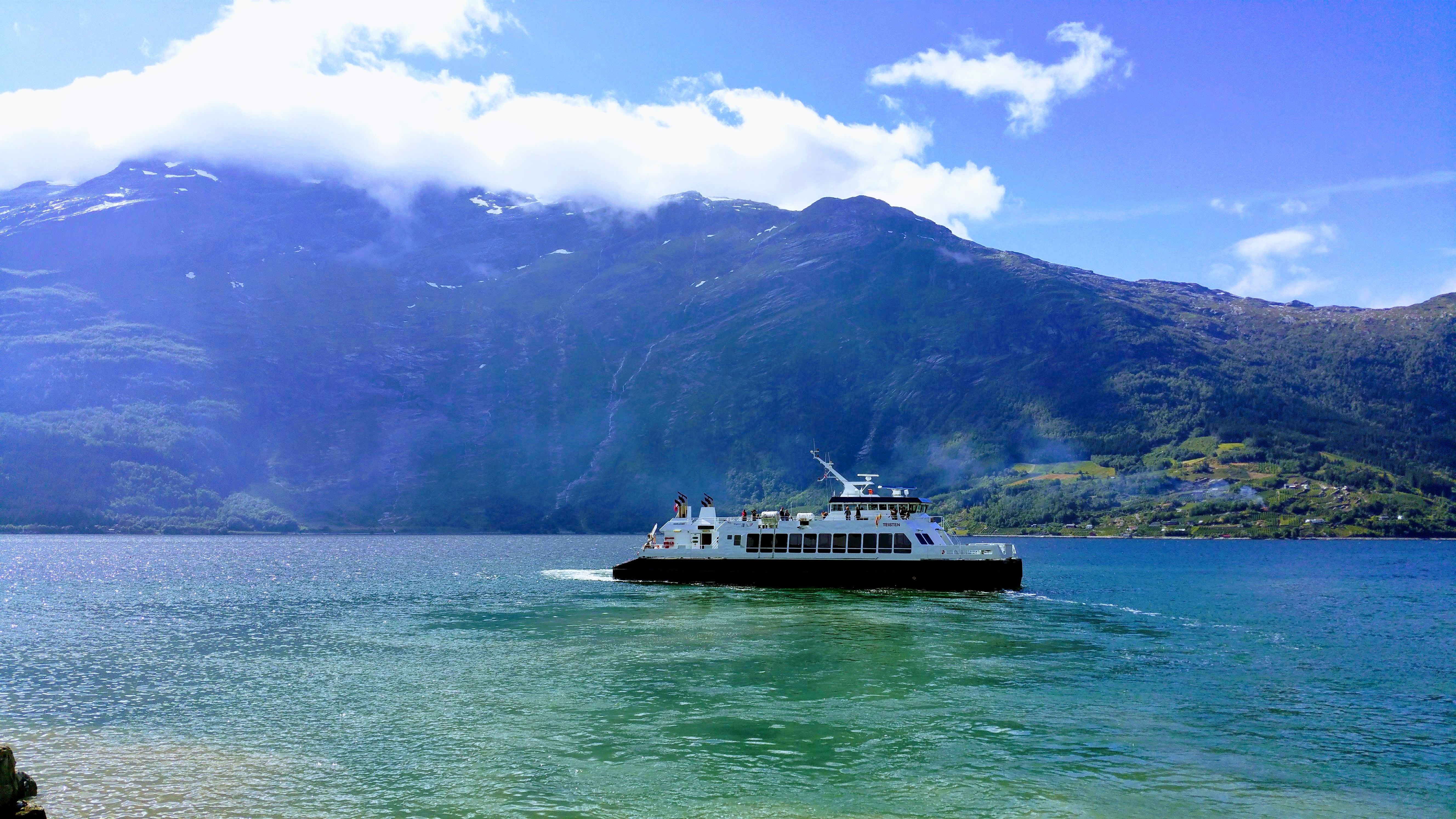 Ferry crossing the Hardangerfjord surrounded by majestic mountains and blue skies – an authentic travel experience in the heart of Hardanger.