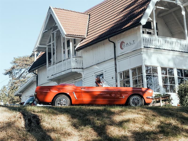 En rød cabriolet foran den hvitmalte Restaurant Salt. Foto.