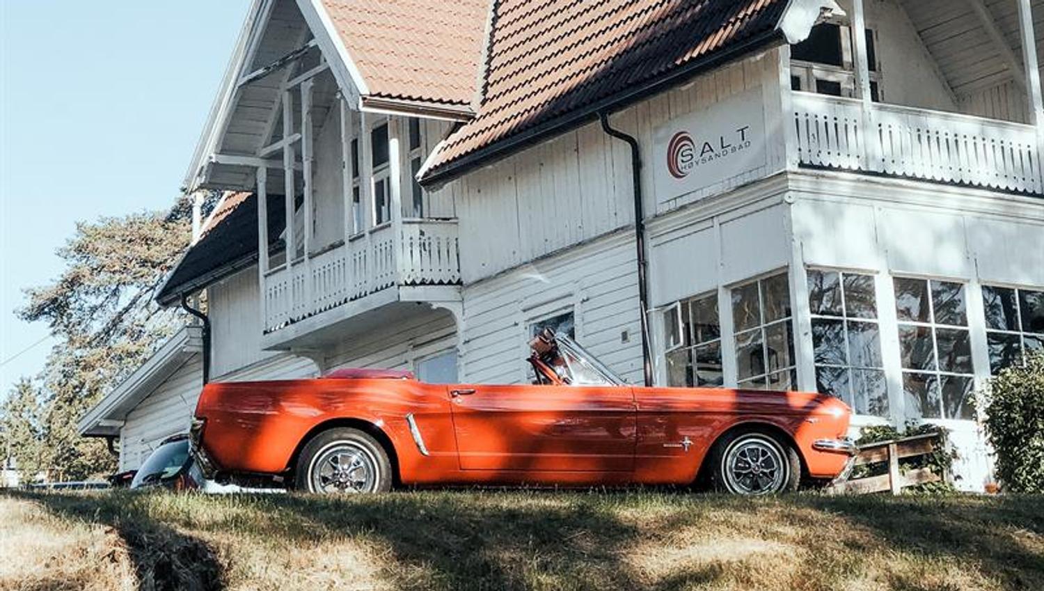 En rød cabriolet foran den hvitmalte Restaurant Salt. Foto.