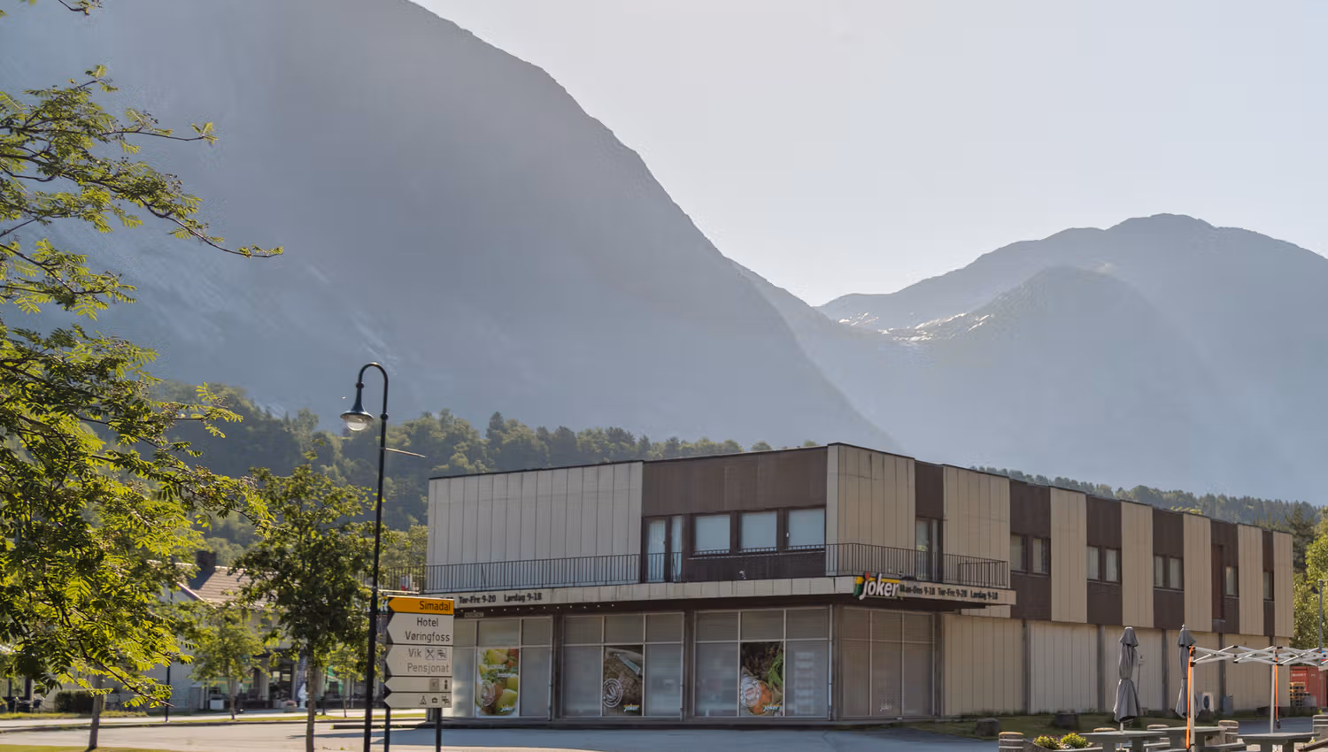 Joker grocery store from the outside, with high mountain in the background on a sunny day.
