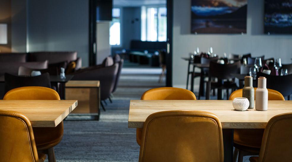 The diningroom at the restaurant with tables, chairs and a view towards the bar area in the background.