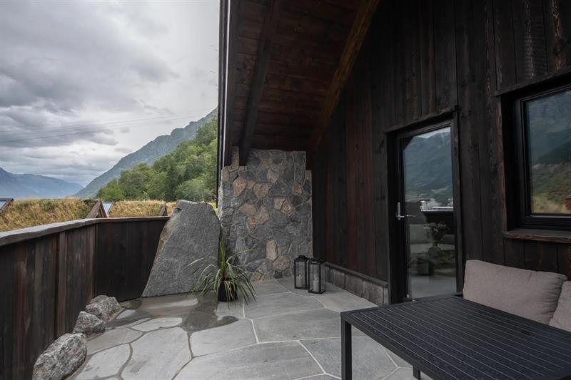 Privat uteareal med steinheller og fjellutsikt utanfor vikinghytte på Lothepus Camping i Odda