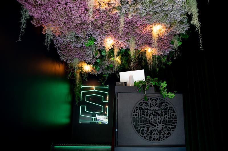 Entrance with vegetation hanging from the ceiling, counter, and a green neon sign