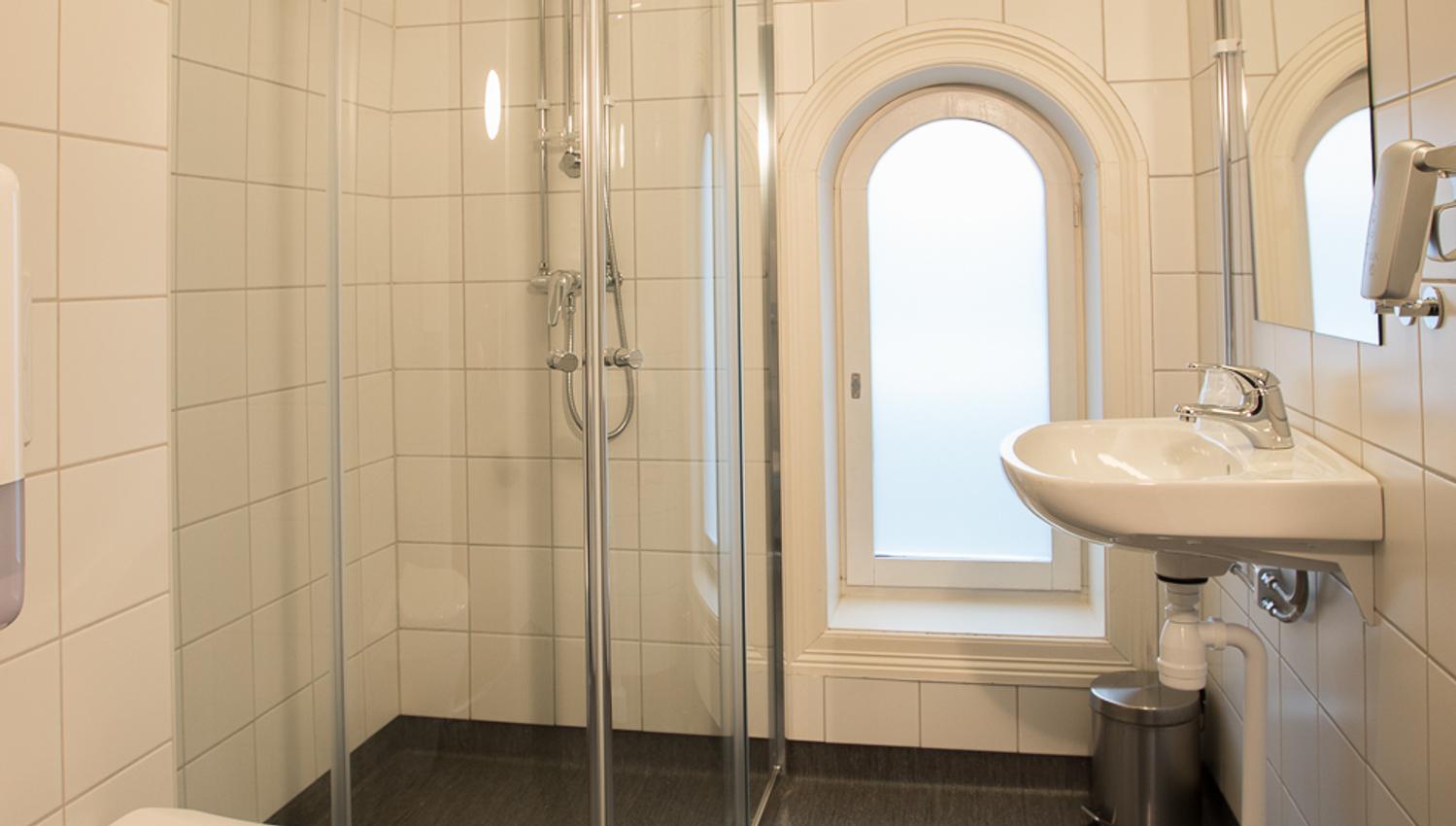 Bathroom with glass shower cabinet. White tiles. Saga Hotel & Poshtel Oslo Central. Photo