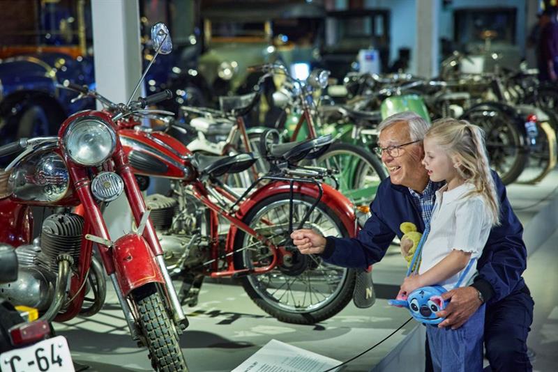 An elderly man and a little girl looking at motorcycles.