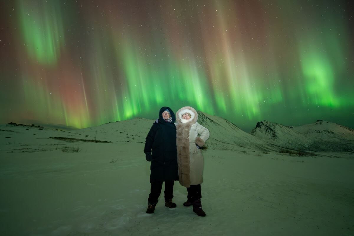 Streams of Aurora dance behind a couple