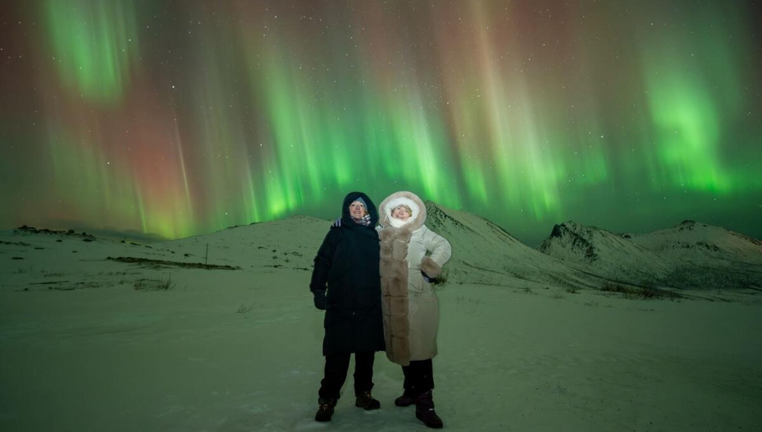 Streams of Aurora dance behind a couple