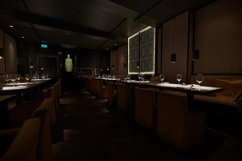 Tables set for dining, chairs, and seating sections against the wall, glass sculpture at the end of the room