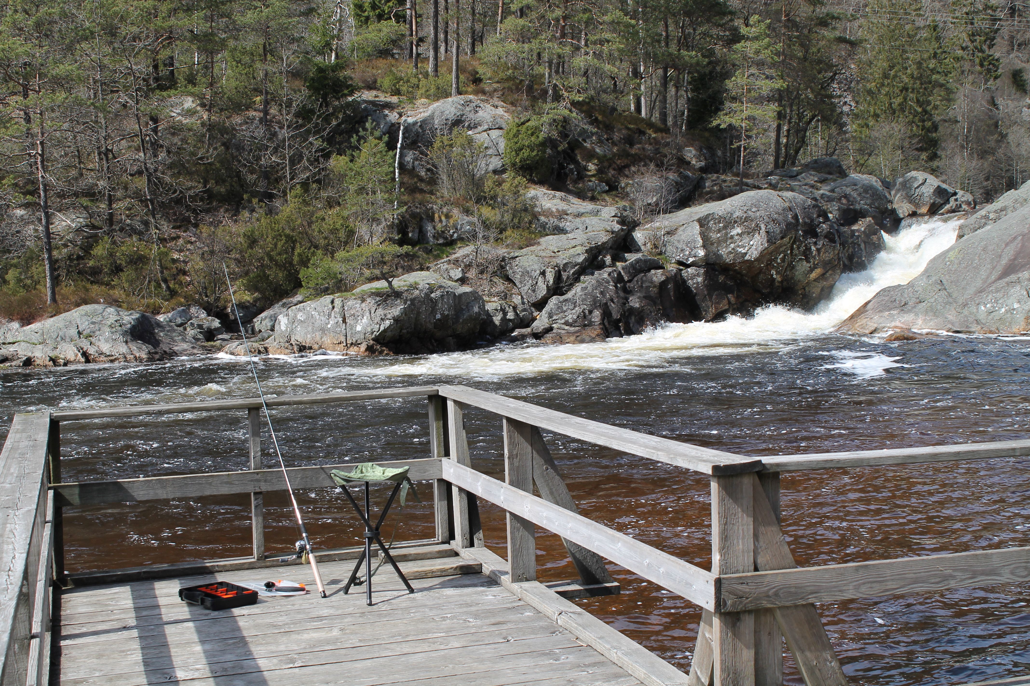 A pier with a fishing rod leaning against the railing, and a deck chair beside it