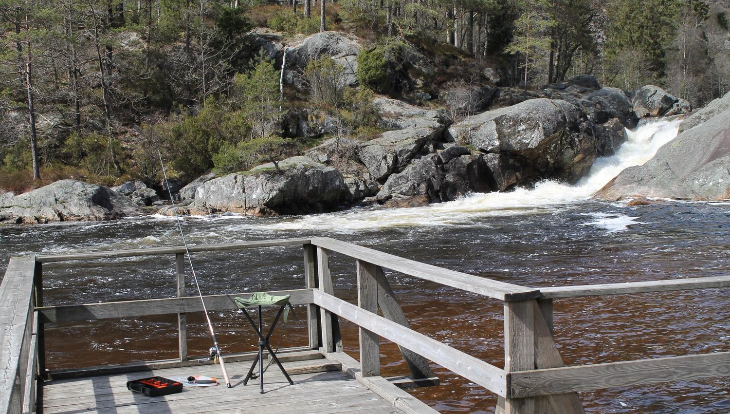 A pier with a fishing rod leaning against the railing, and a deck chair beside it