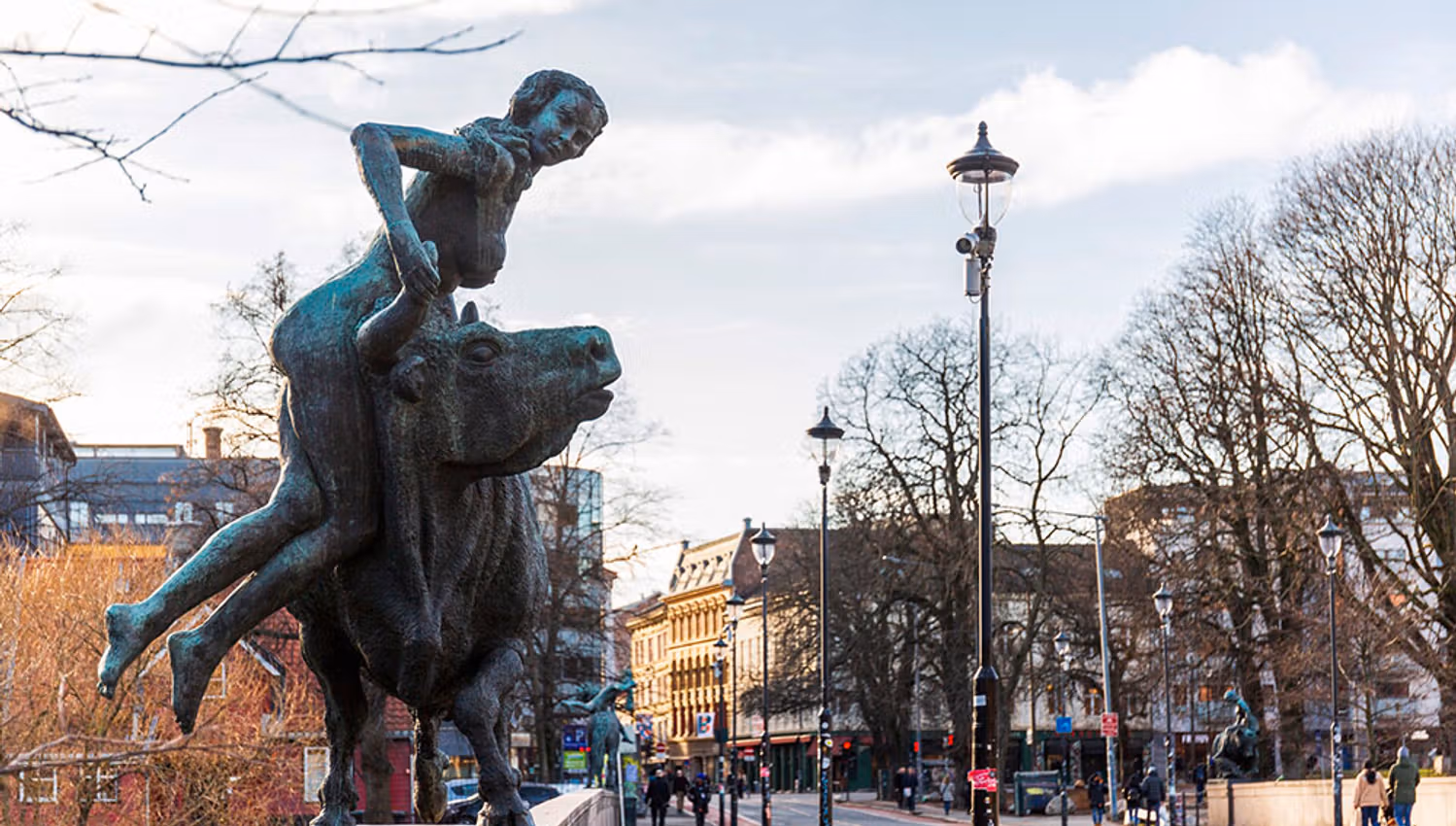 En statue av en jente som henger fra en okse langs brua.
