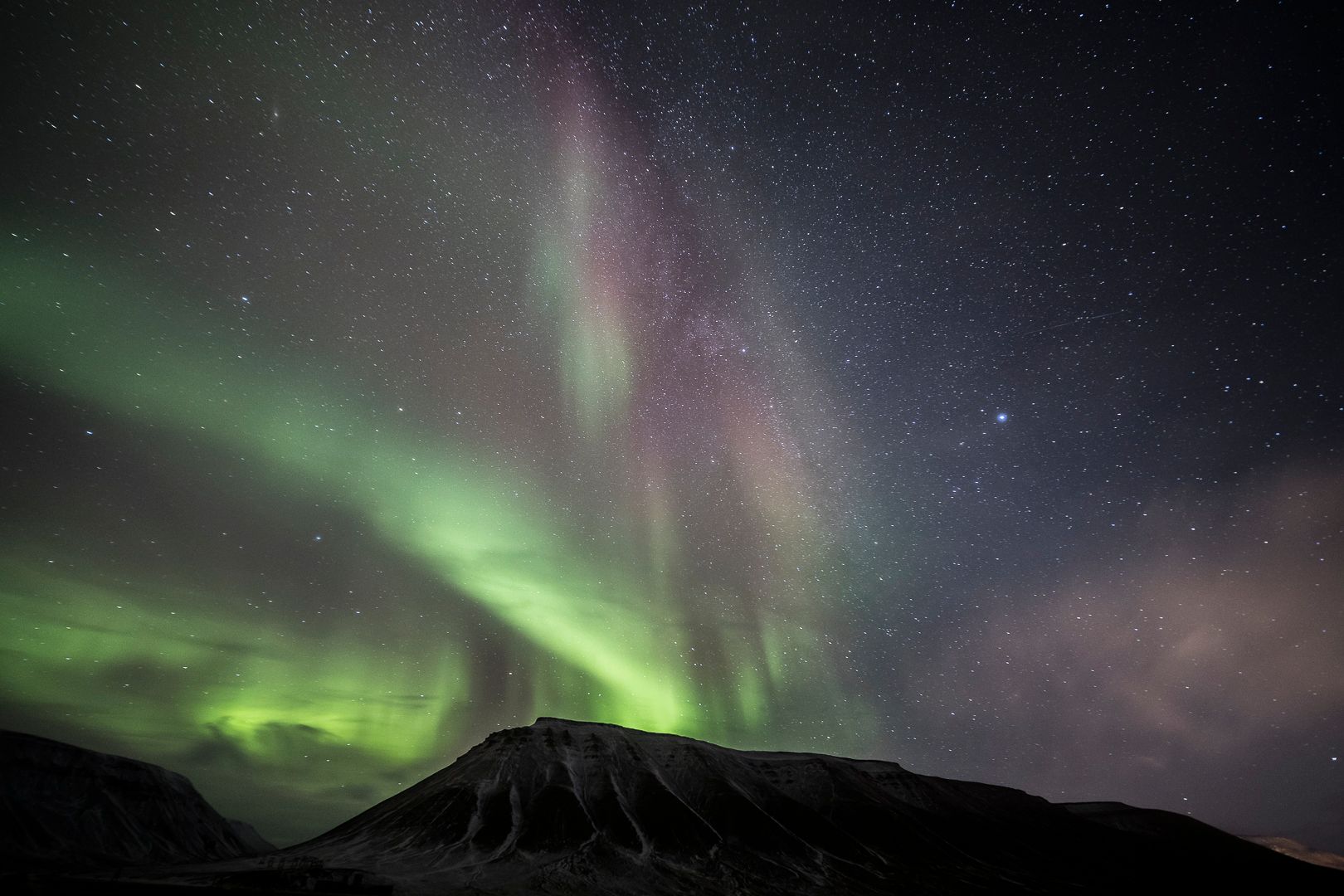 Green northern lights above the mountains