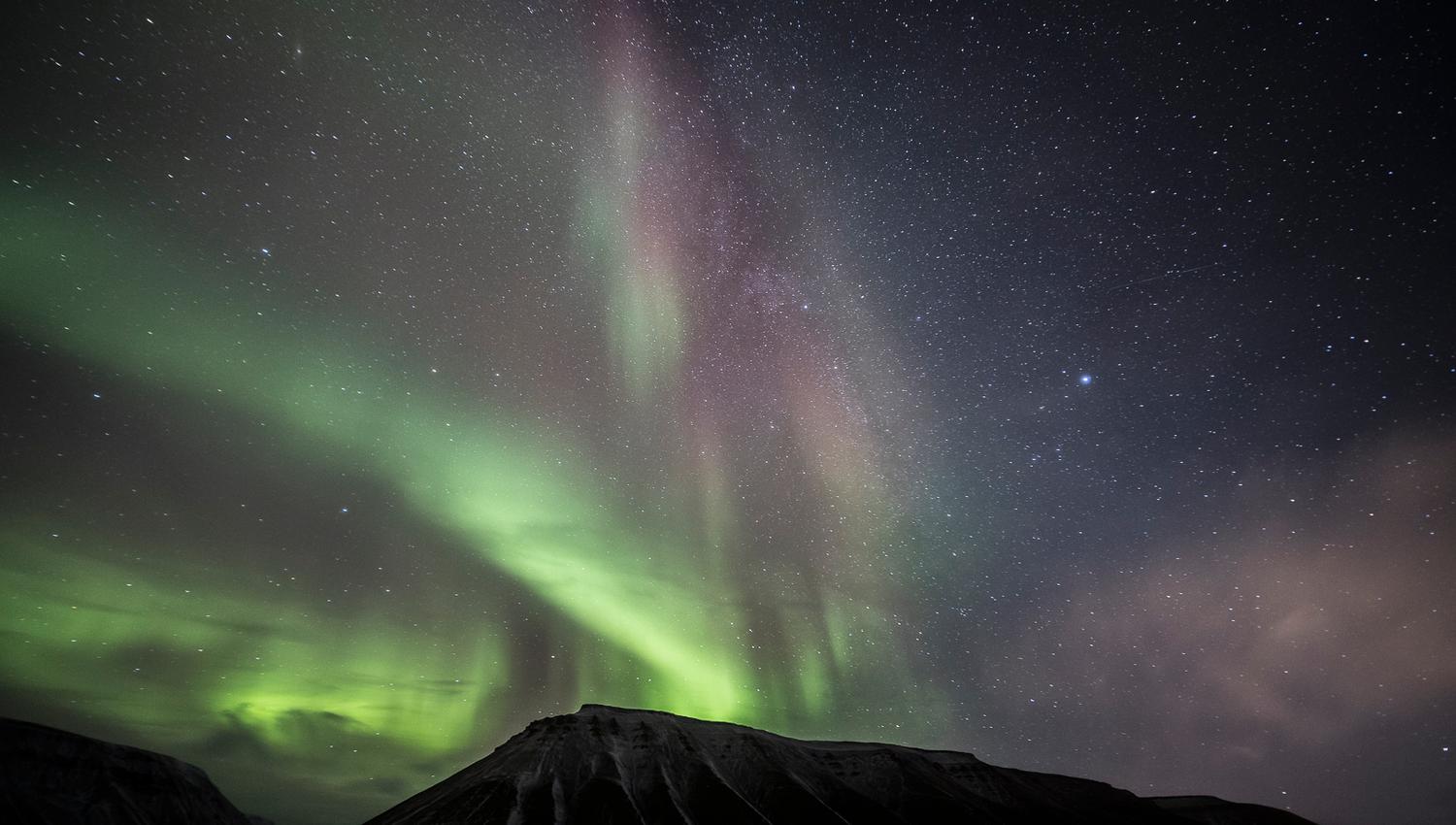 Green northern lights above the mountains