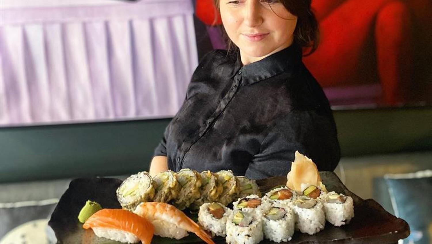 Waitress carrying a sushi plate.