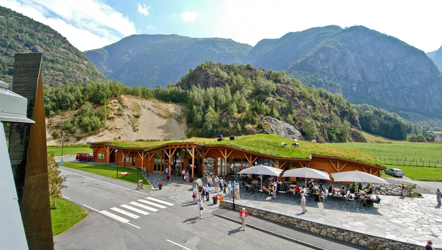 Hardangerviddahallen, a wooden buiding with grass and goats on the roof, seen from the outside.