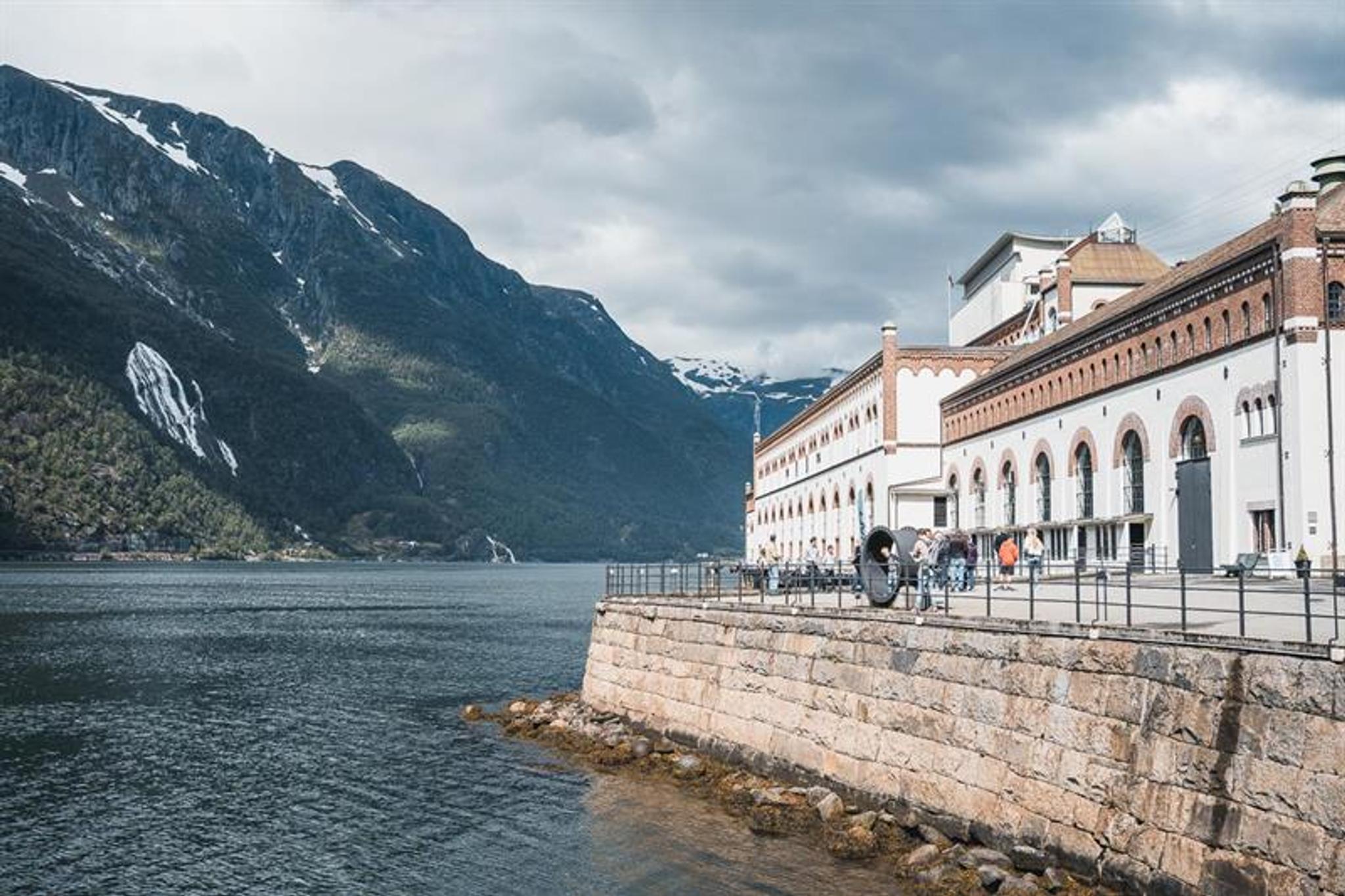Bygningar frå Kraftmuseet i Hardanger med utsikt over fjorden, omgitt av vakre fjell og norsk natur.