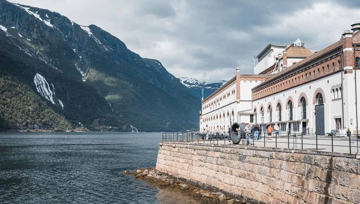 The historic buildings of the Kraftmuseet in Hardanger, overlooking the fjord, surrounded by stunning mountains and Norwegian nature.