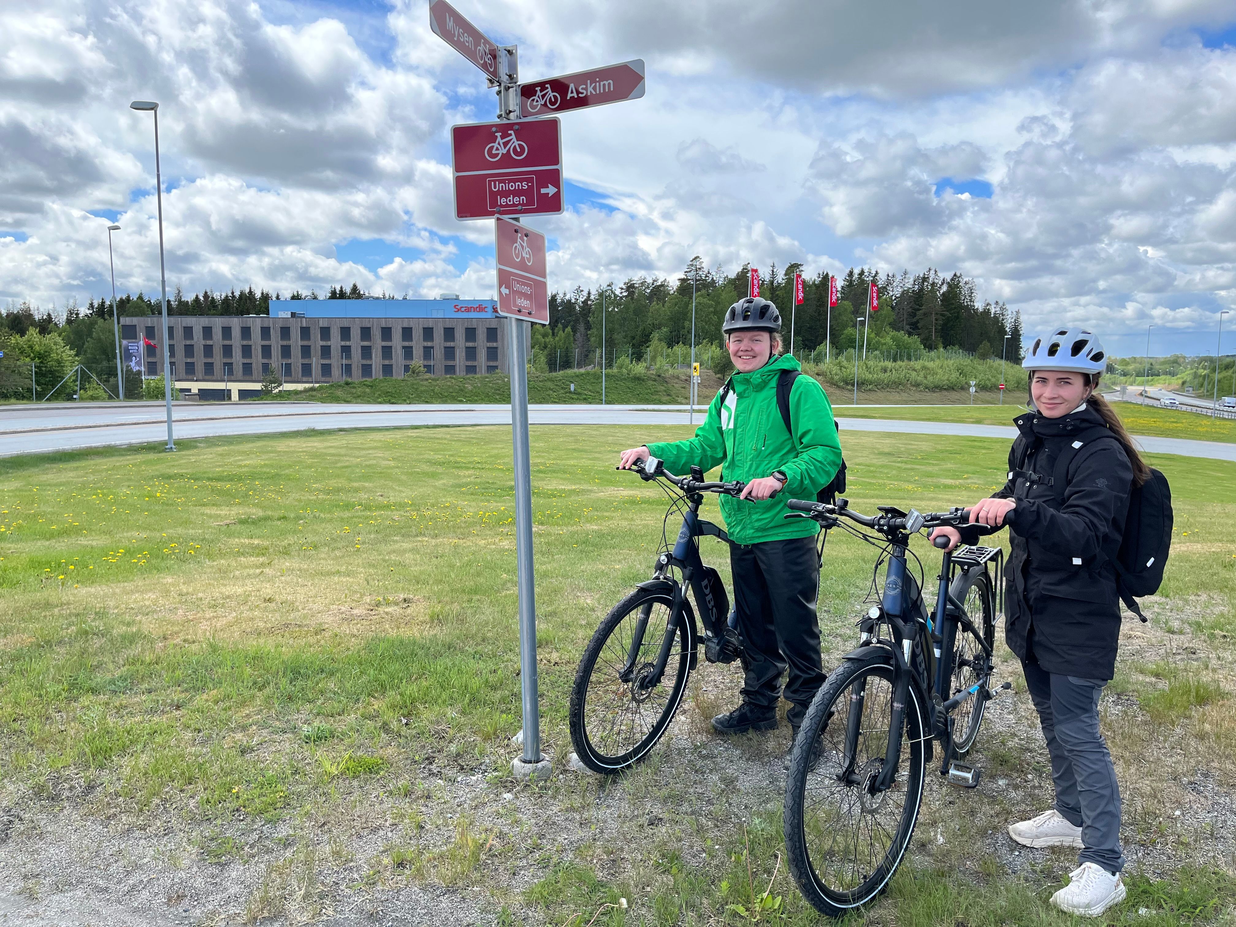 Syklister står ved stolpe