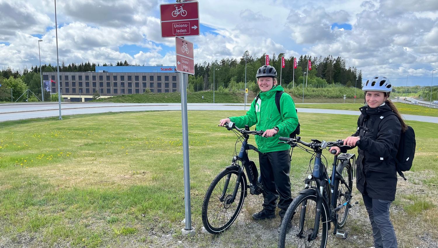 Syklister står ved stolpe