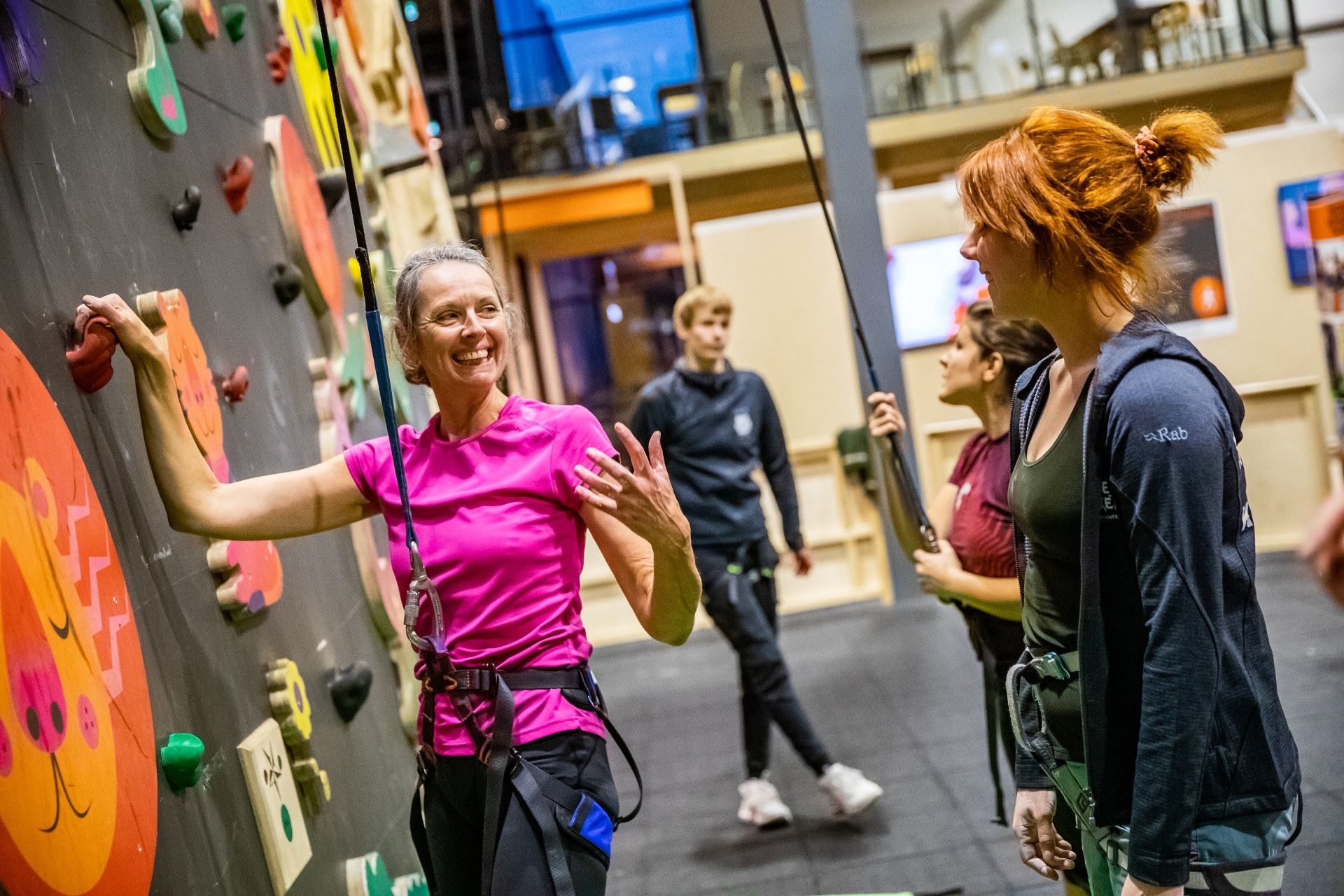 Adults smile at the climbing wall