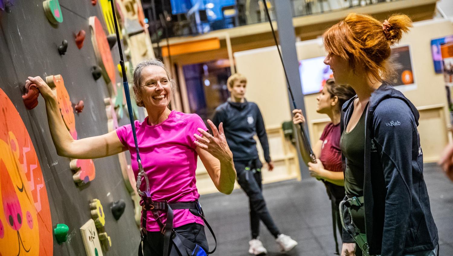 Adults smile at the climbing wall