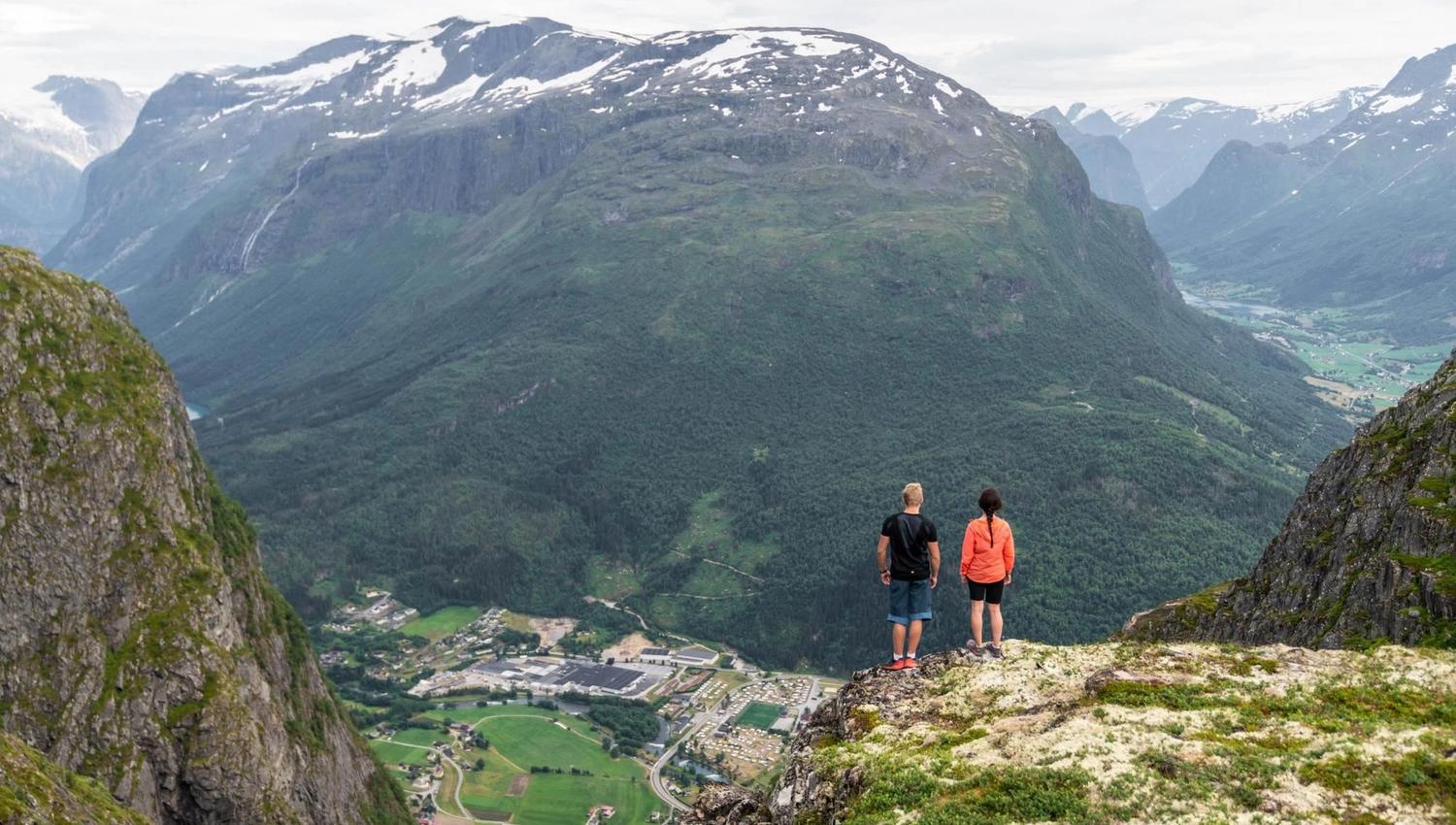 Two hikers taking a break on the mountain above Loen, overlooking the fjord and mountains.