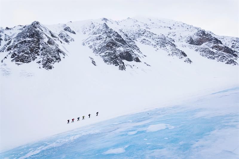 En gruppe mennesker går opp et fjell på ski