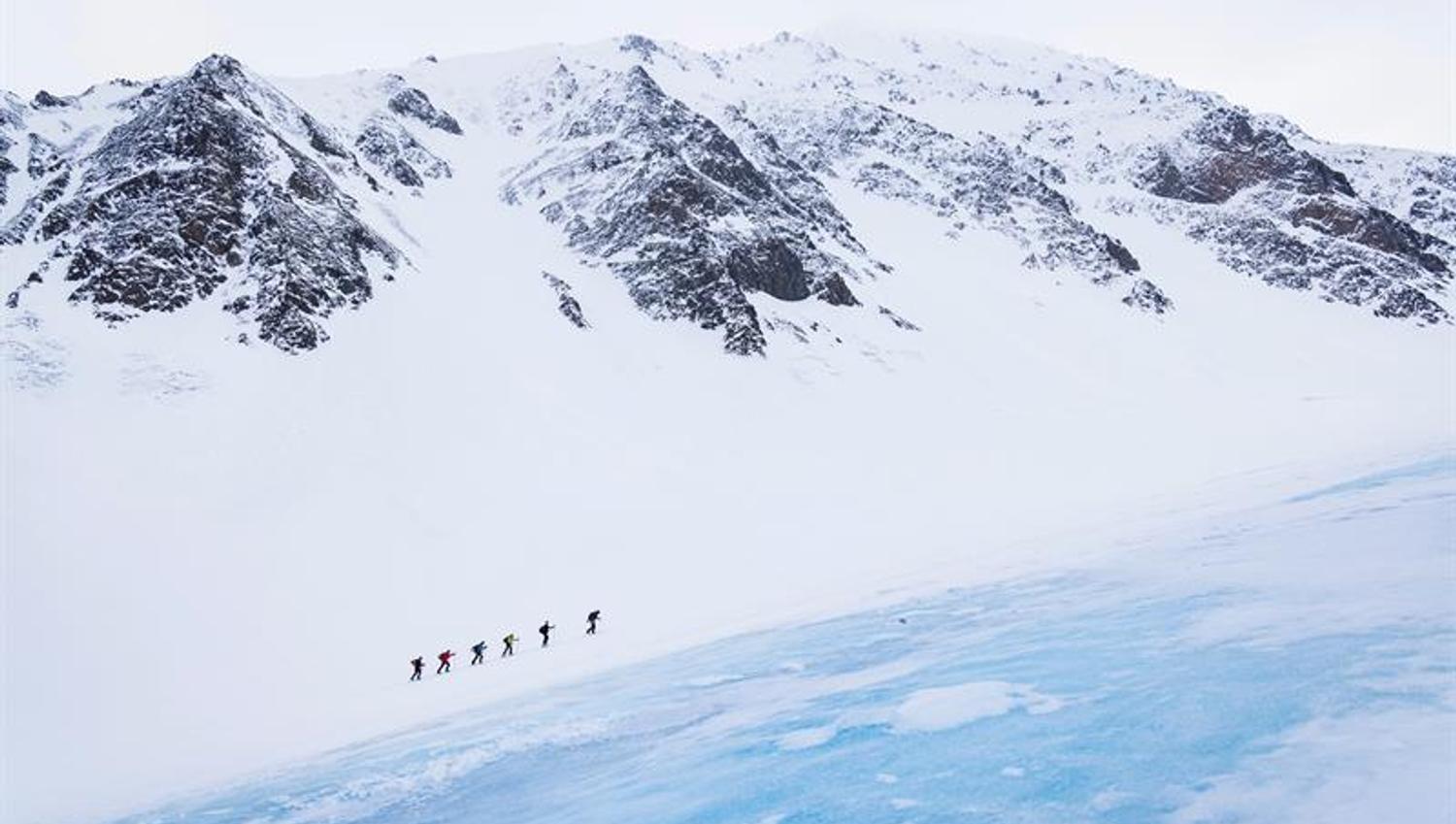 En gruppe mennesker går opp et fjell på ski
