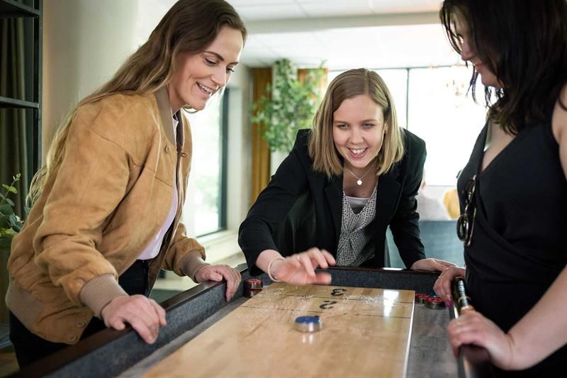 Tre damer som spiller shuffleboard