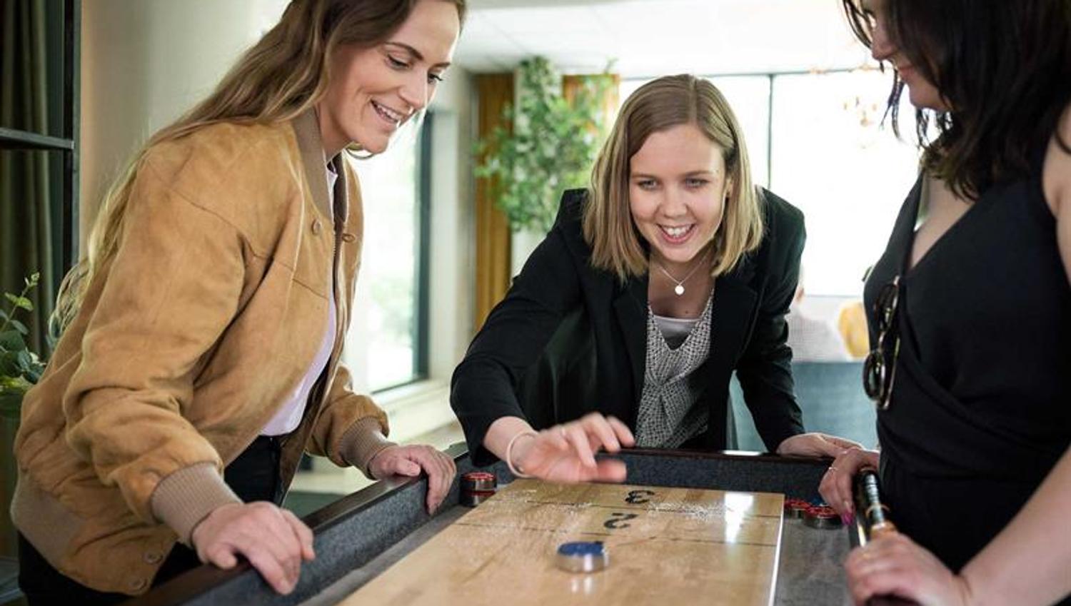 Tre damer som spiller shuffleboard