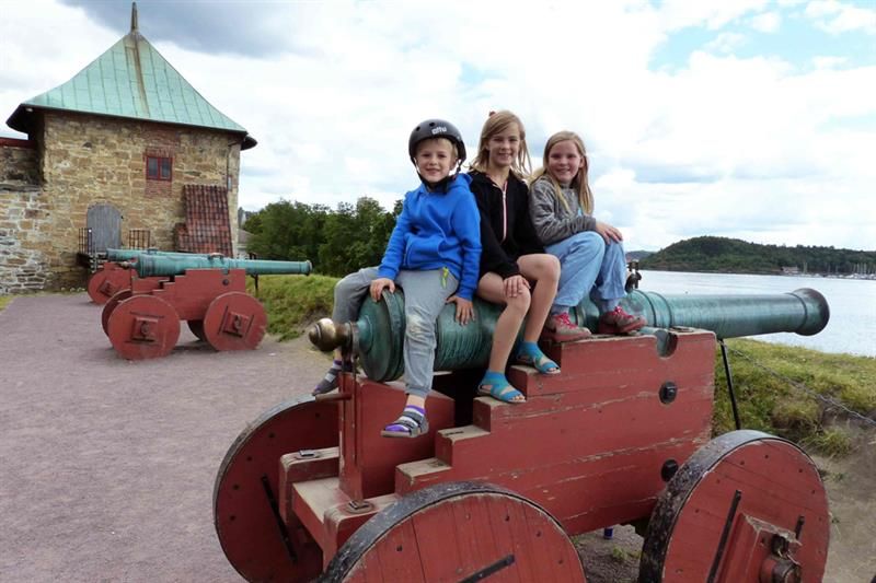 Three children sitting on a cannon.