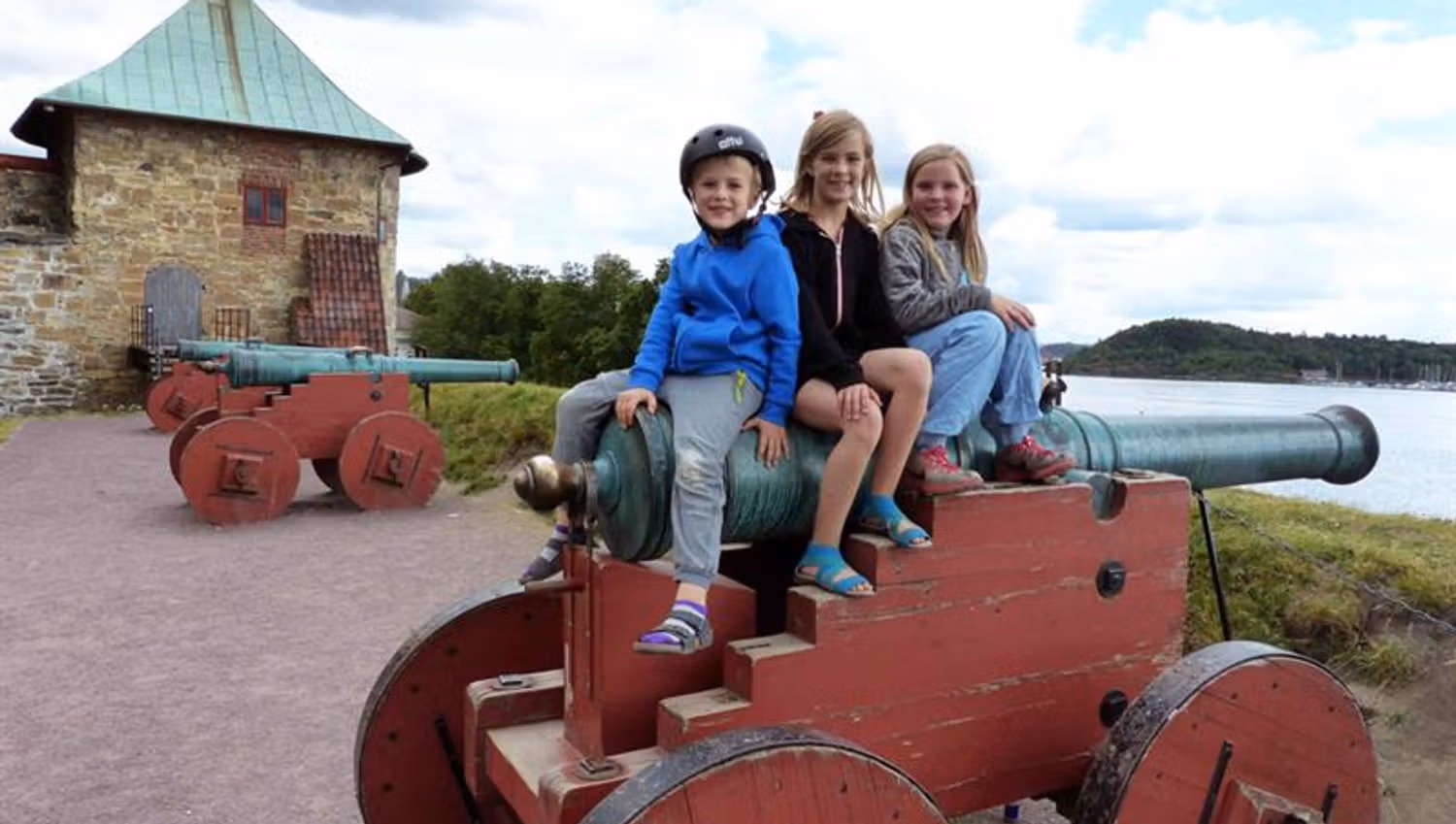 Three children sitting on a cannon.