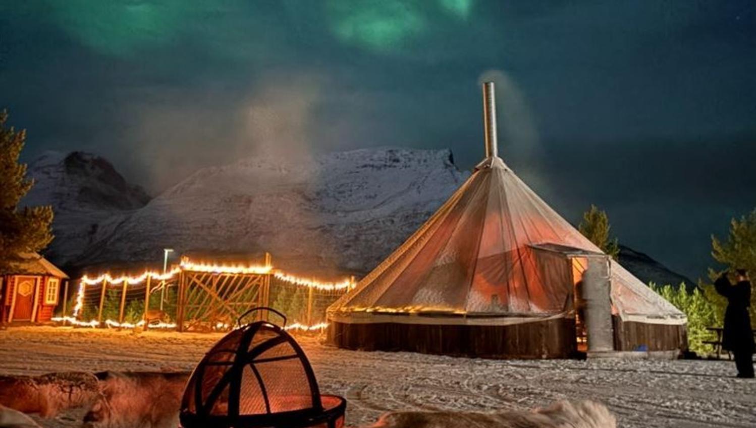 Fire pit and a traditional lavvu under the Northern Lights in Skibotn