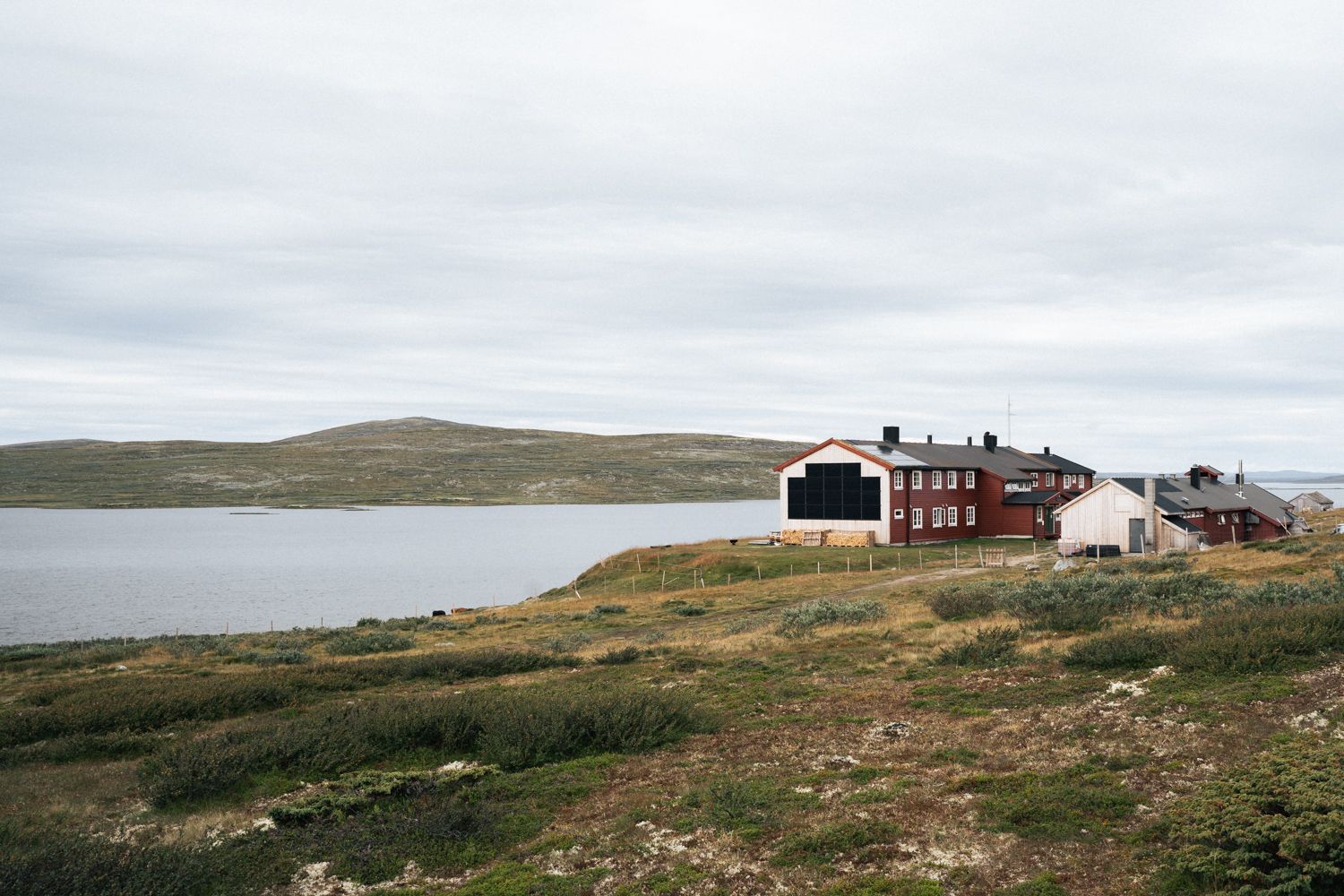 A view of the Rauhelleren mountain lodge from the outside, with the lake in front.
