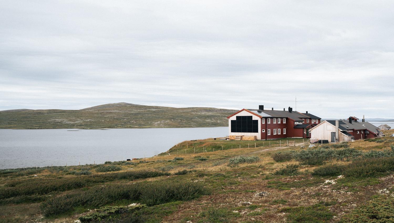A view of the Rauhelleren mountain lodge from the outside, with the lake in front.