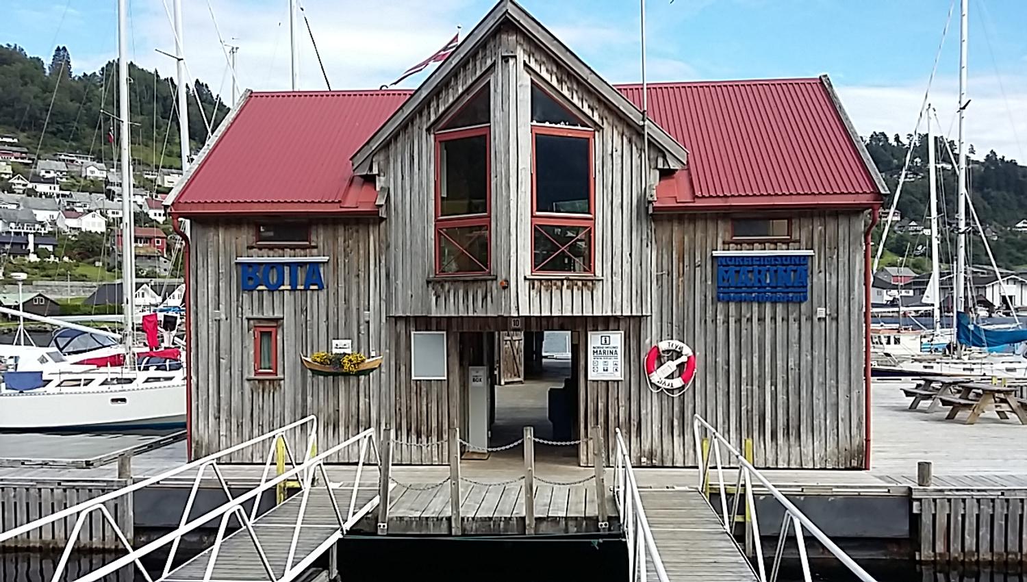 Entrance to Norheimsund Marina with signage, wooden structure, and guest harbour in the background.