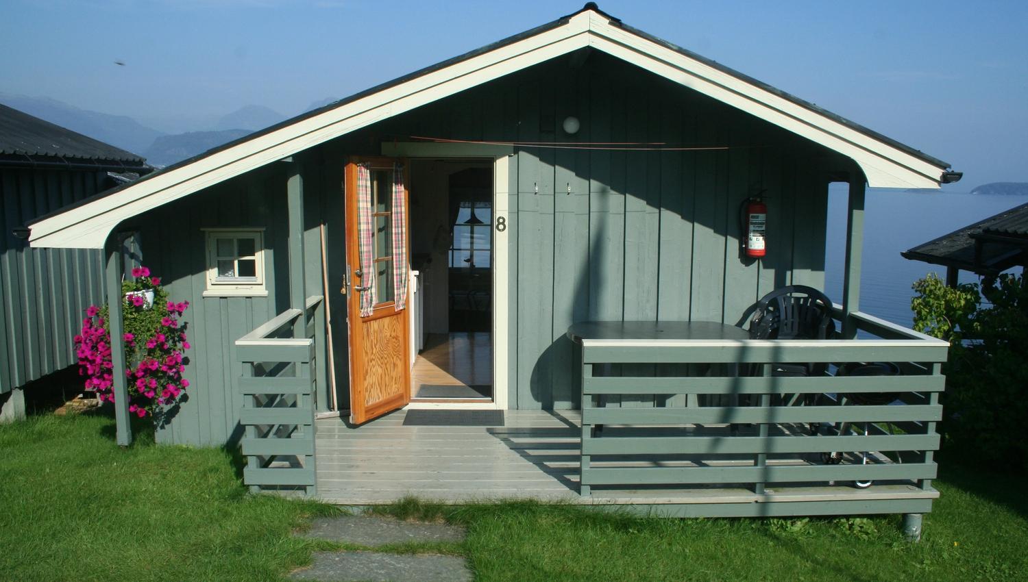 Open cabin at Oddland Camping showing the living area and view of the Hardangerfjord.