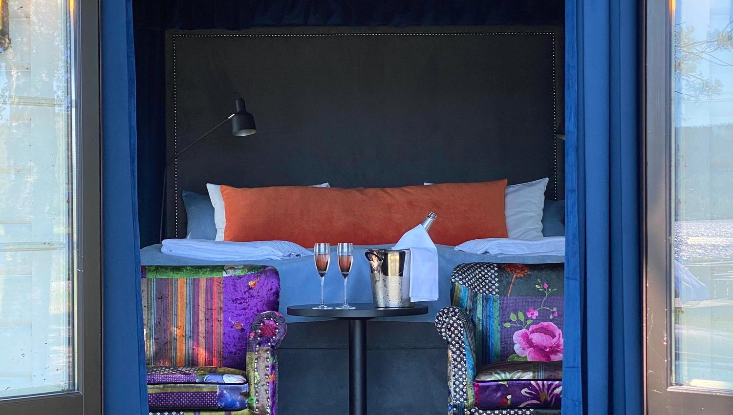 2 chairs with flowery cover, 2 glasses with champagne in a room seen from outside