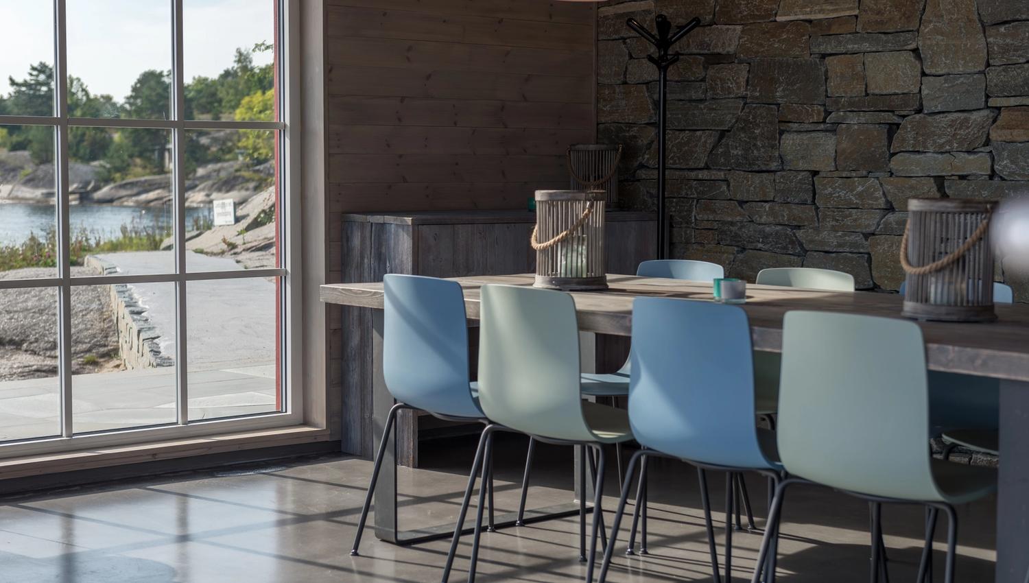 Blue and green chairs at a long table by the window